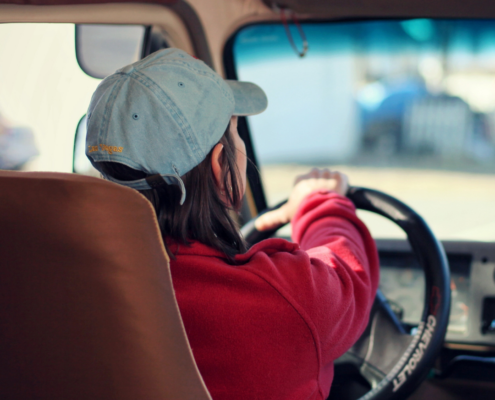 Photo of a woman in a red jacket driving a vehicle.