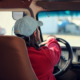Photo of a woman in a red jacket driving a vehicle.