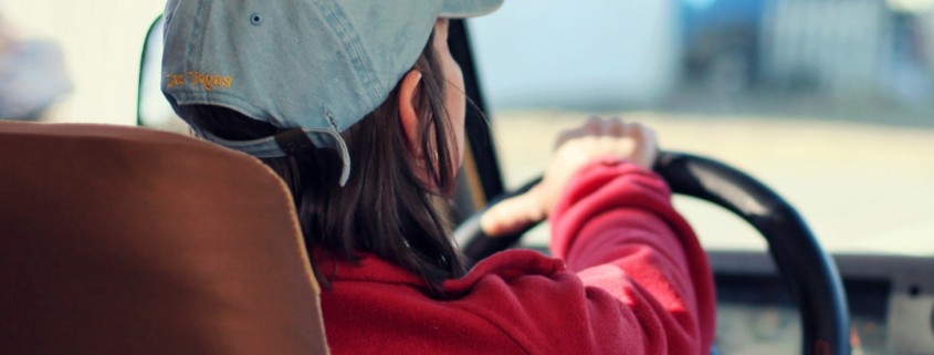 Photo of a woman in a red jacket driving a vehicle.