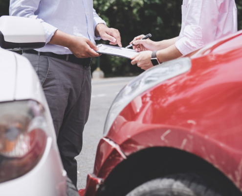 Two individuals discussing paperwork after a car accident
